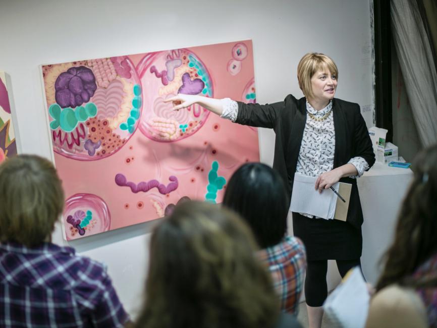 A professor points to a pink painting