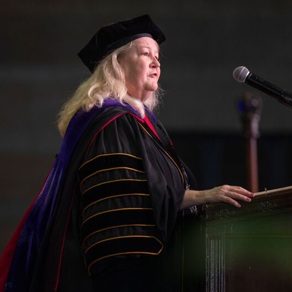 a woman in academic robes speaks at a apodium