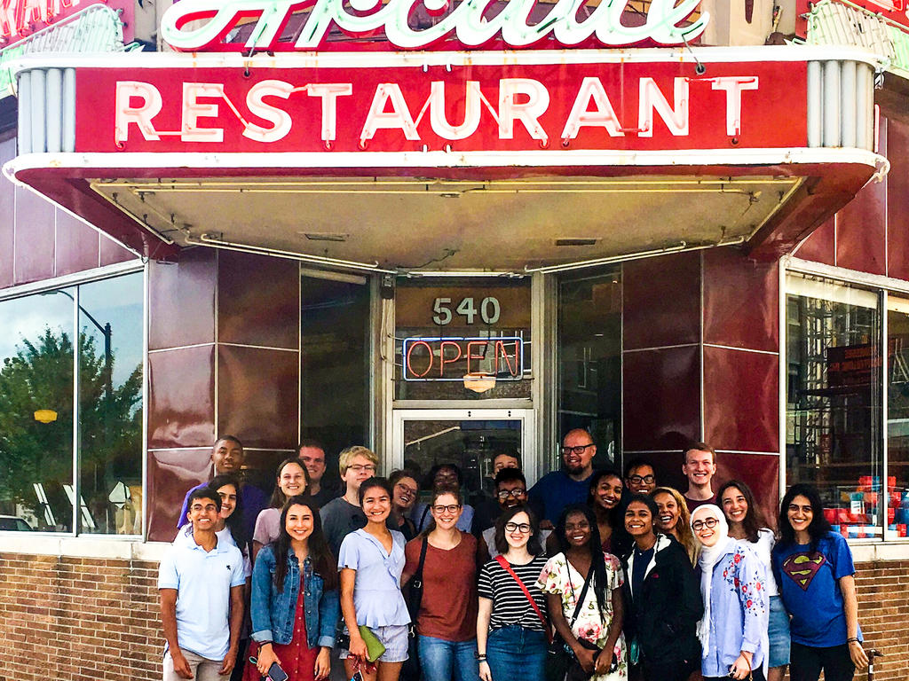 group of students standing outside in front of a restaurant