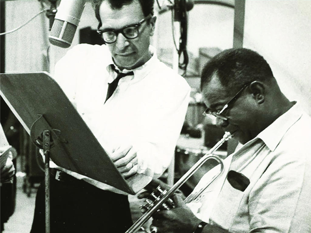 a black and white picture of jazz musicians reading music while playing their instruments