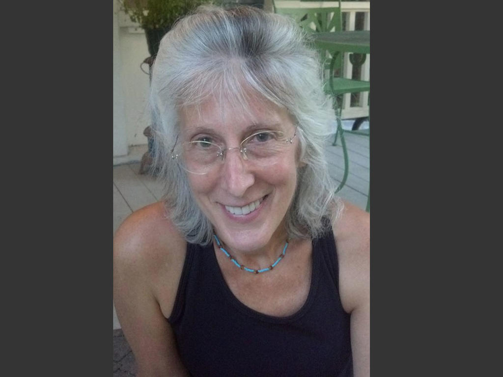 an older white female professor sitting casually on a porch in a tank top