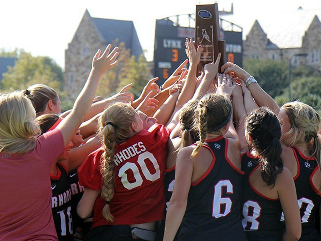 a group of girls victoriously raising a trophy above their heads
