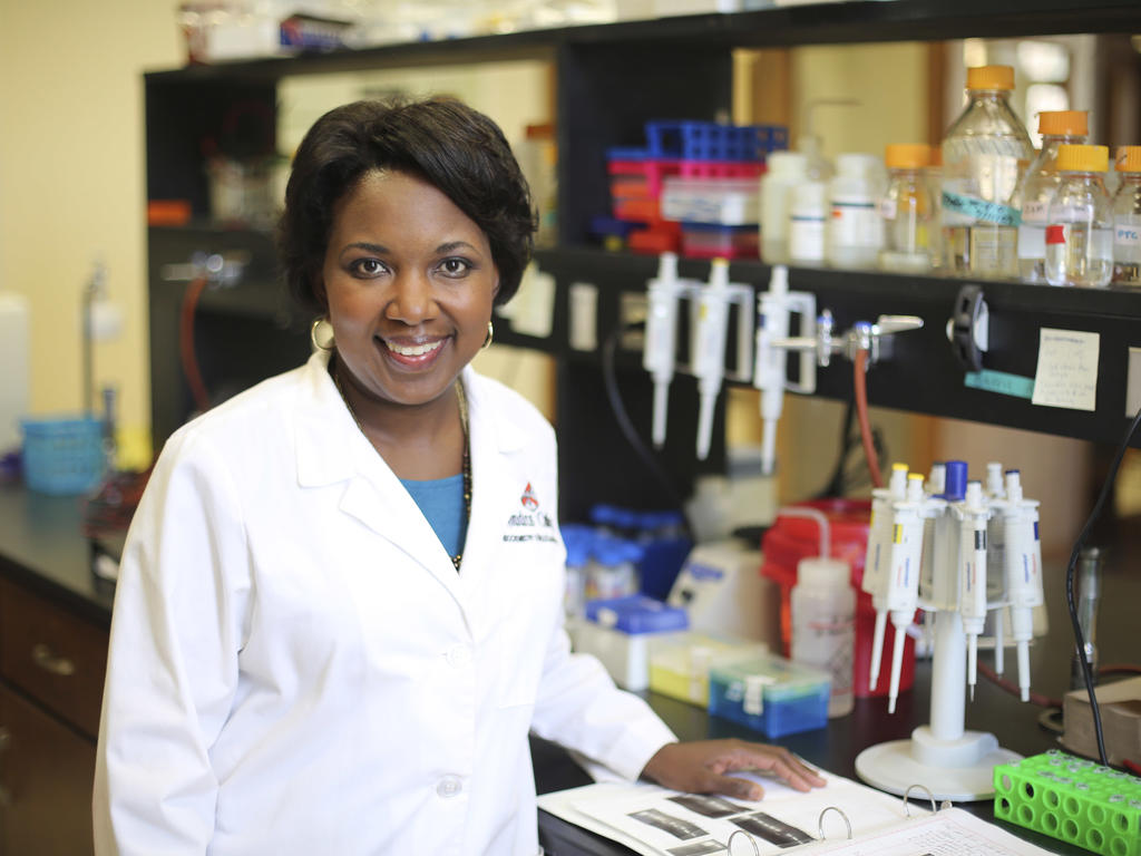 an african american woman in a lab coat standing in her chemistry laboratory