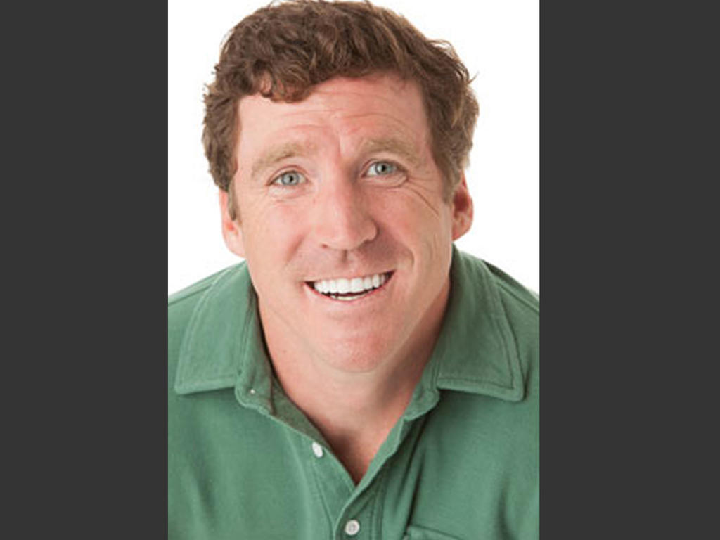 a middle-aged white male's headshot with him wearing a green shirt and smiling upwards at the camera