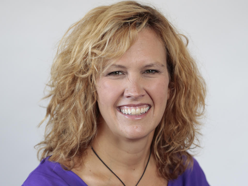 smiling blonde female professor in a purple top