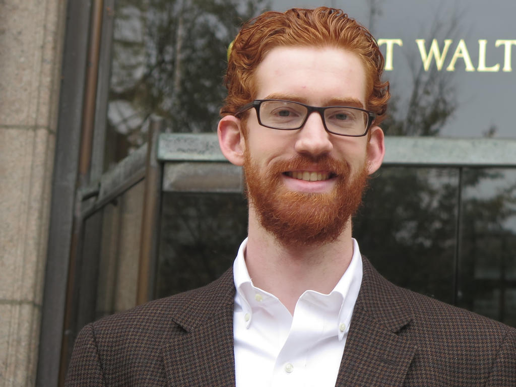 a middle-aged man wearing a suit, sporting glasses and curly, red hair and beard