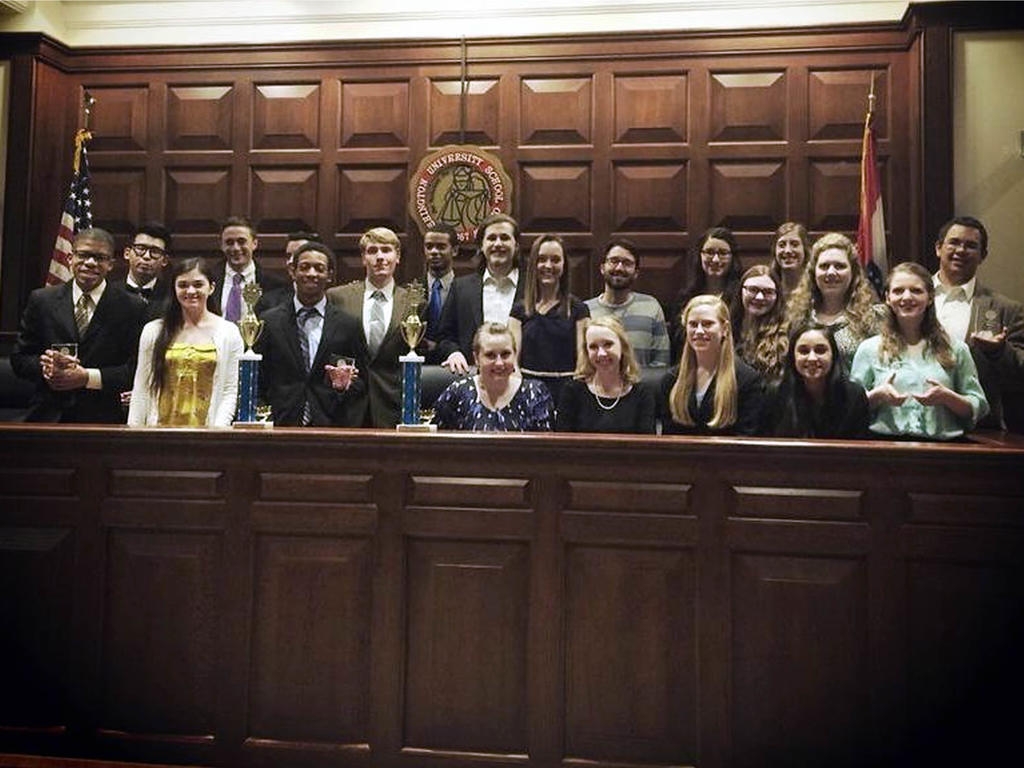 a diverse group of students smiling proudly in the courtroom