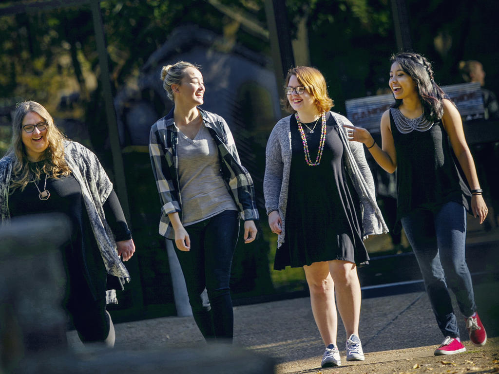 a group of four young women casually strolling and talking