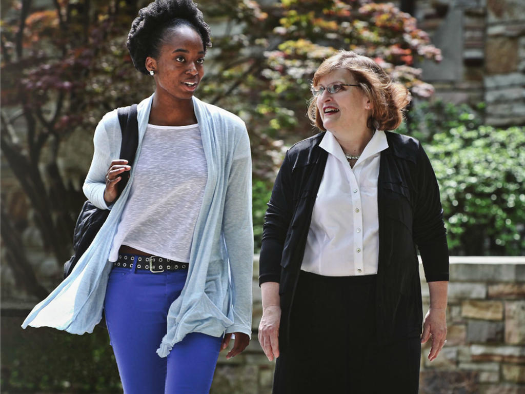 a young african american woman strolling through campus white a middle-aged white female professor