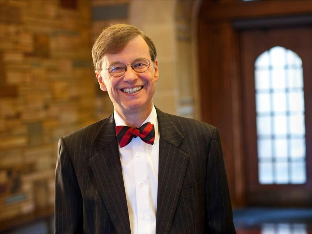 an older white male wearing a suit and bow tie smiling excitedly