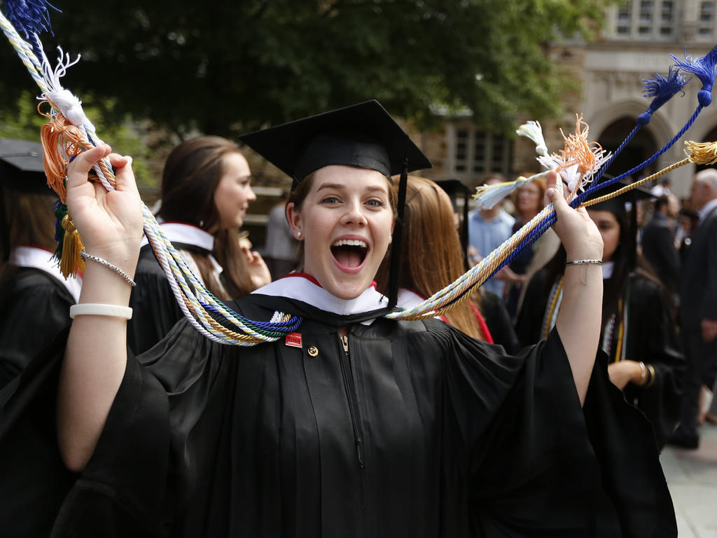 a female graduate ecstatically throwing her cords in the air in celebration