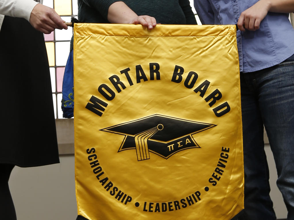 a yellow fabric banner that has the mortar board logo and name on it