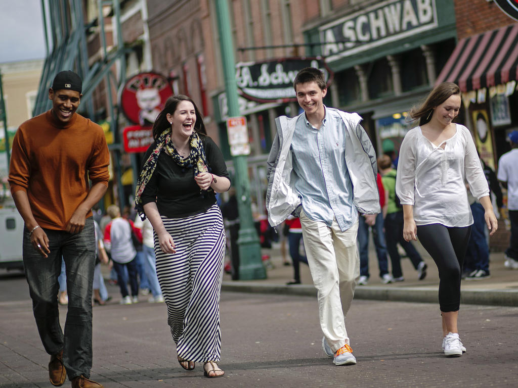 Four young people laughing and walking down the street