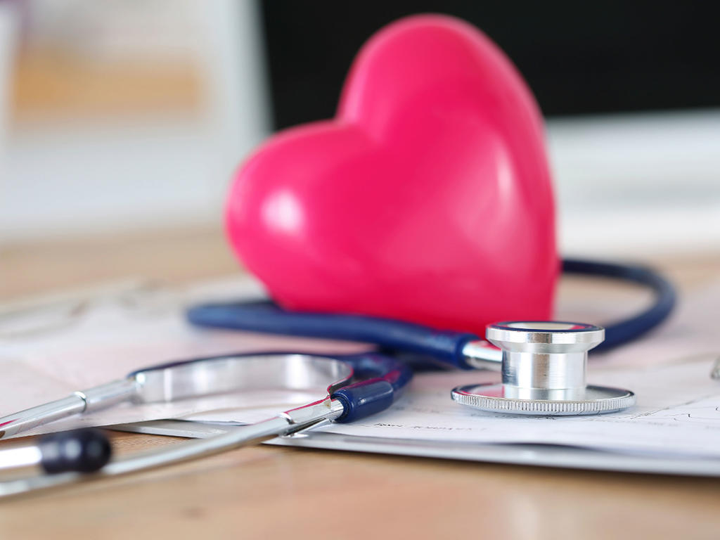 a stethoscope on a wooden table with a plastic cartoon heart