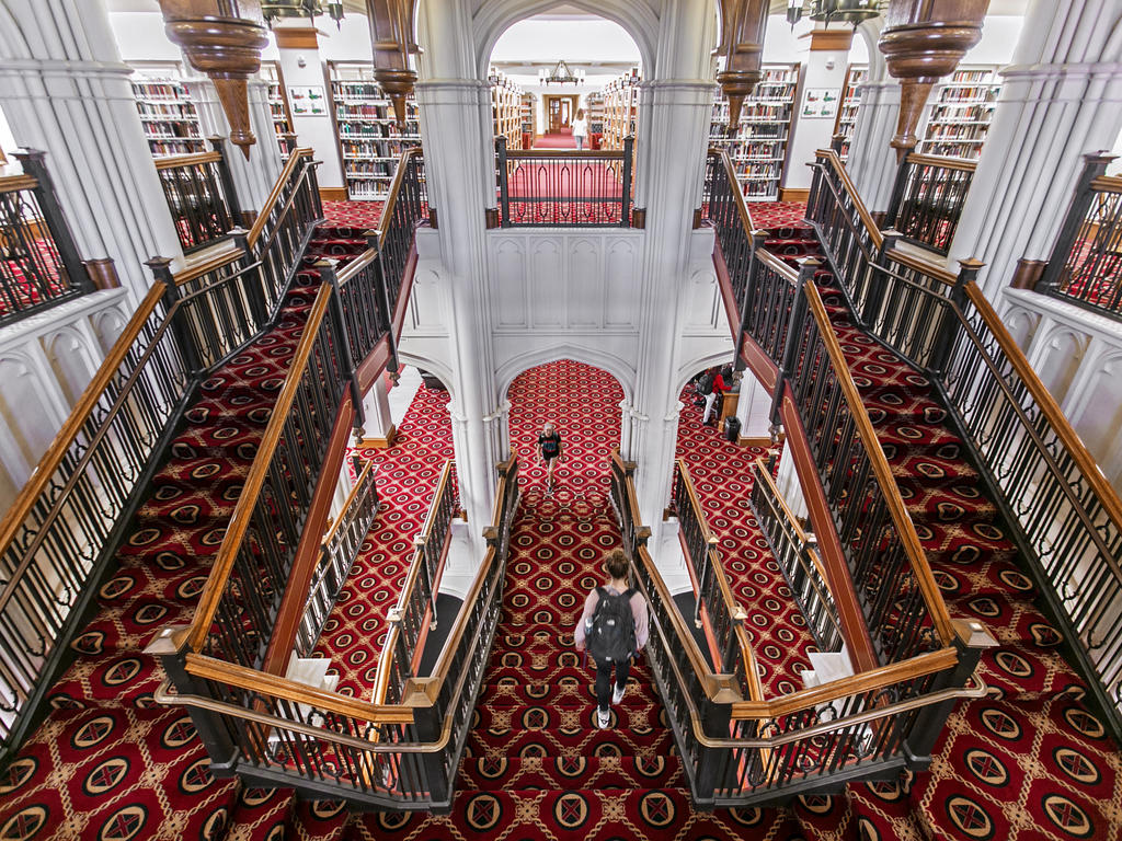 a grand staircase with red carpeting and ornate wooden banisters