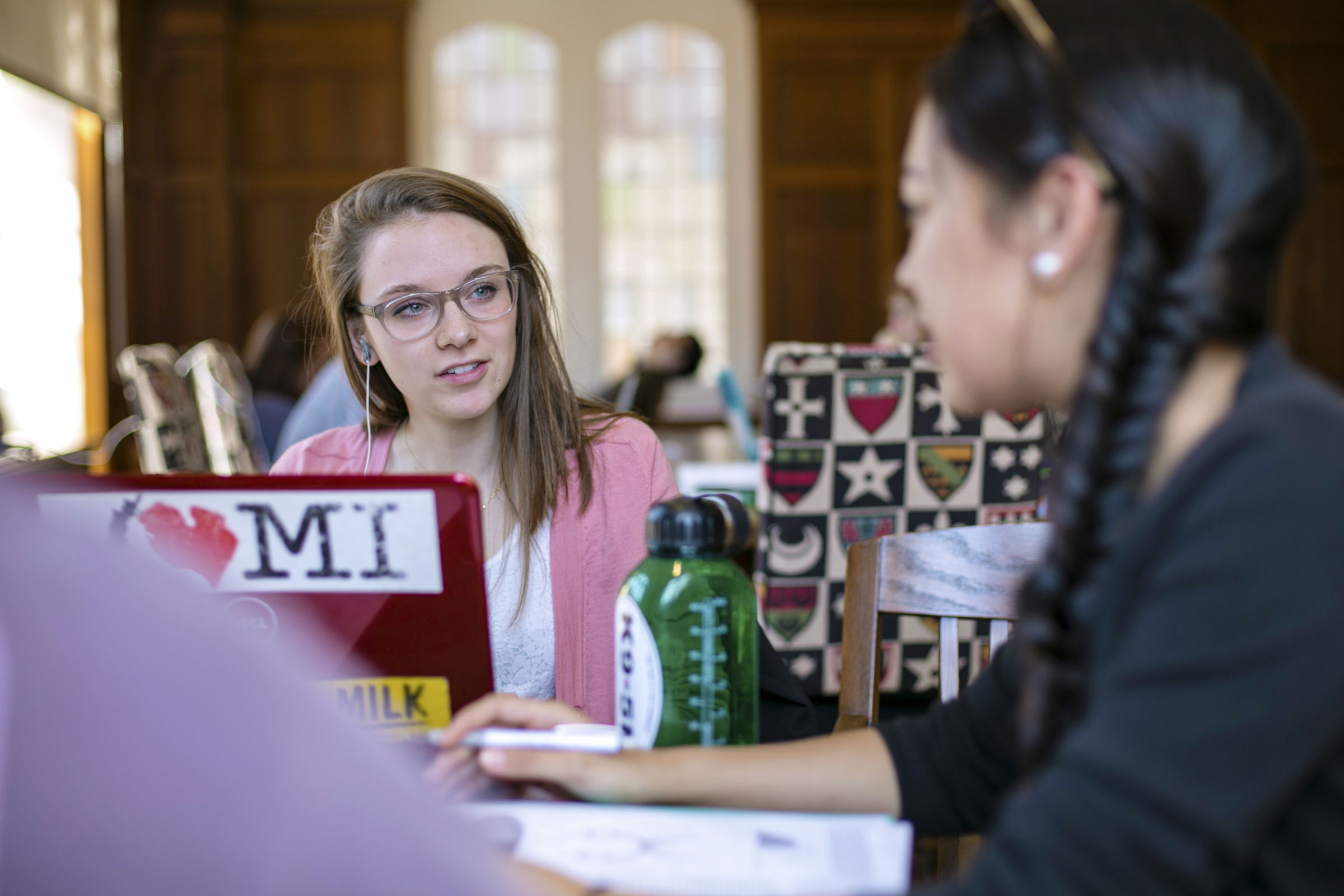 two students with a laptop talking around a table