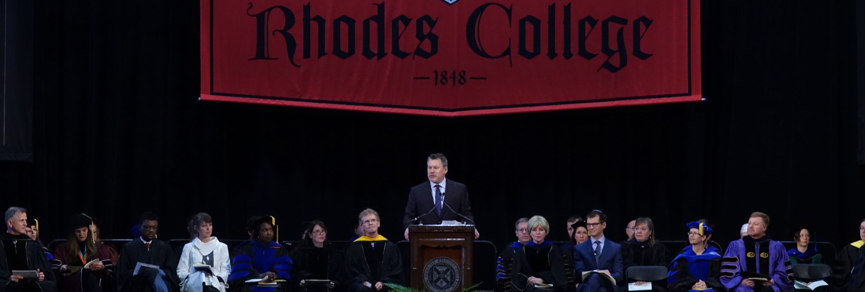 A man and several faculty members on stage