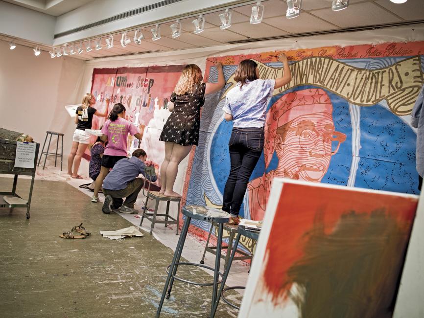 Students paint a mural on an interior wall