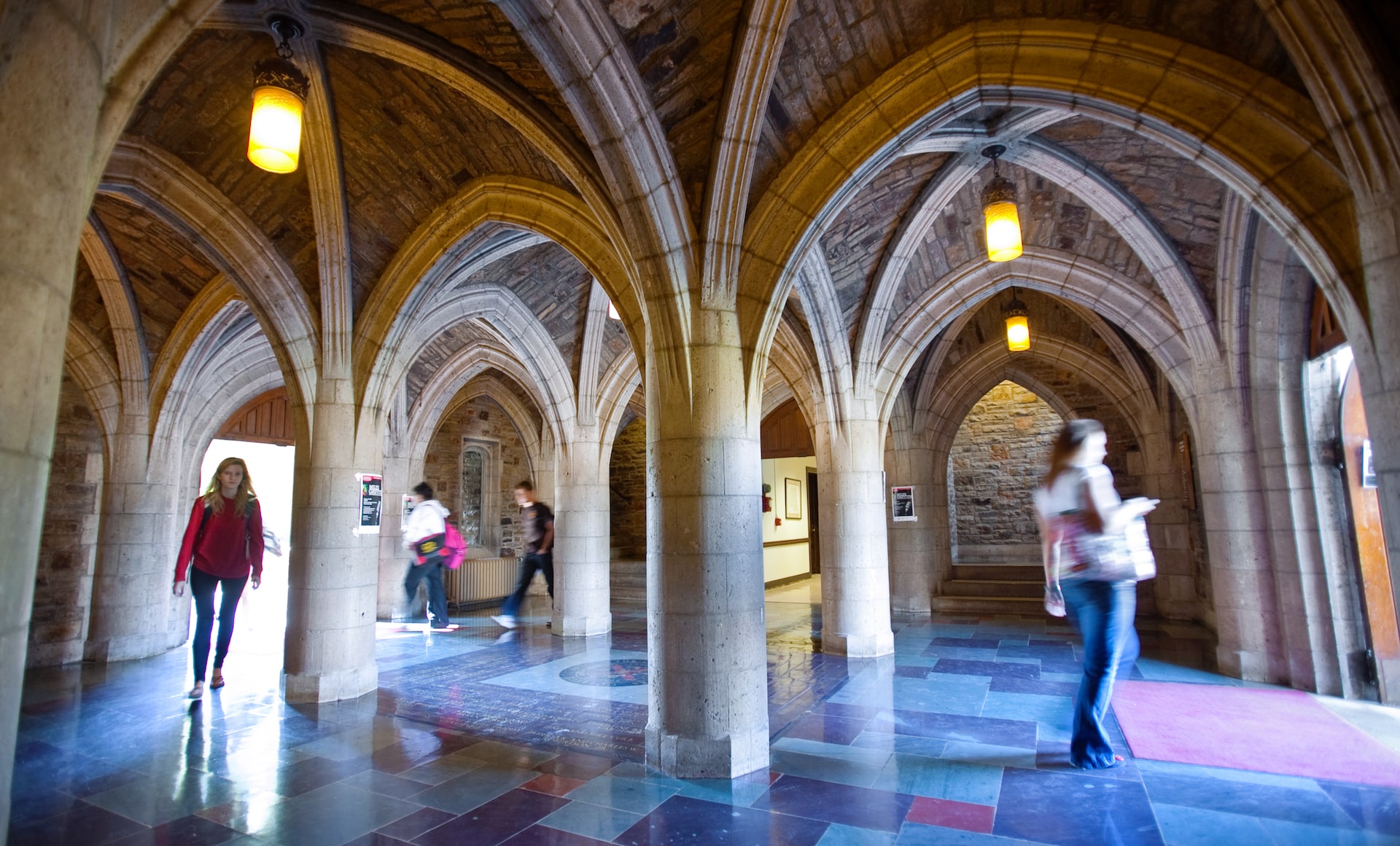 Students walking through a series of stone arches.