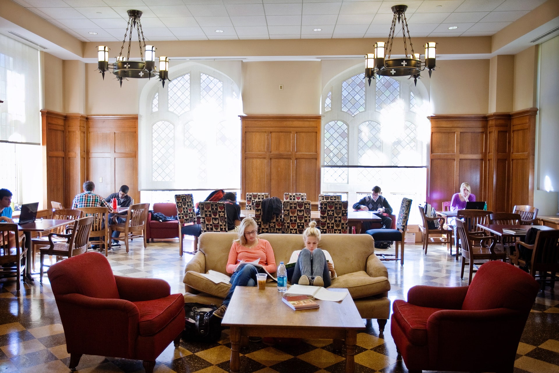 Students studying in a large, bustling common room next to a coffee stand.