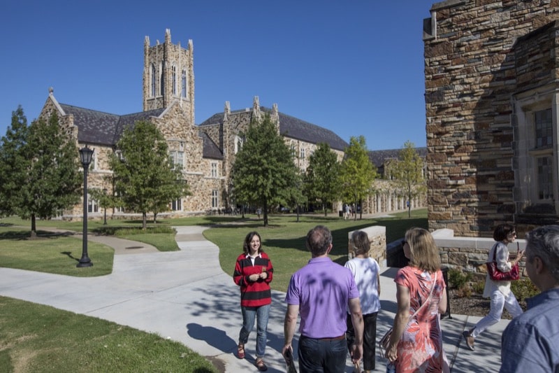 A student in a red and black rugby jersey leads a tour on a beautiful spring morning.