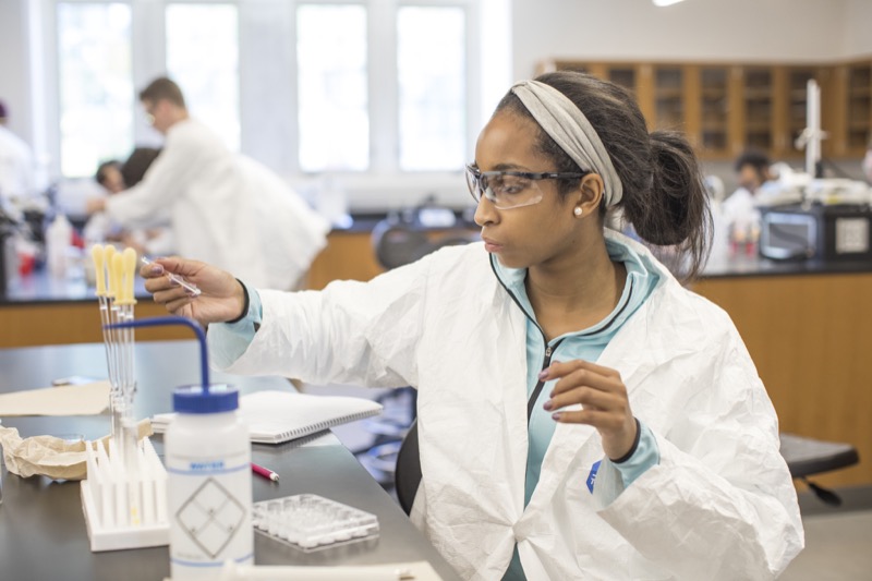 A student in a lab coat adjusts her equipment.