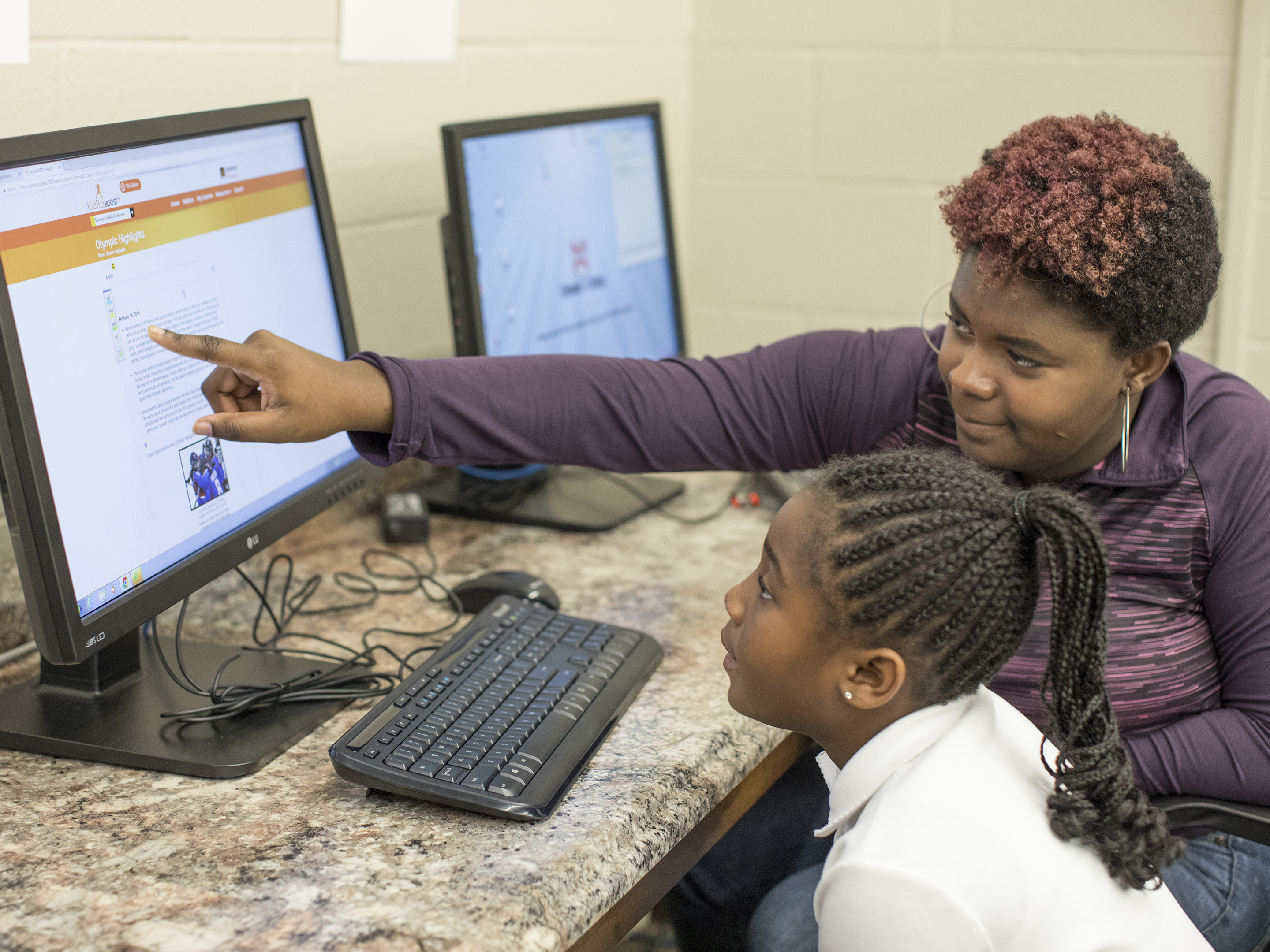 a college student helps a young girl at a computer