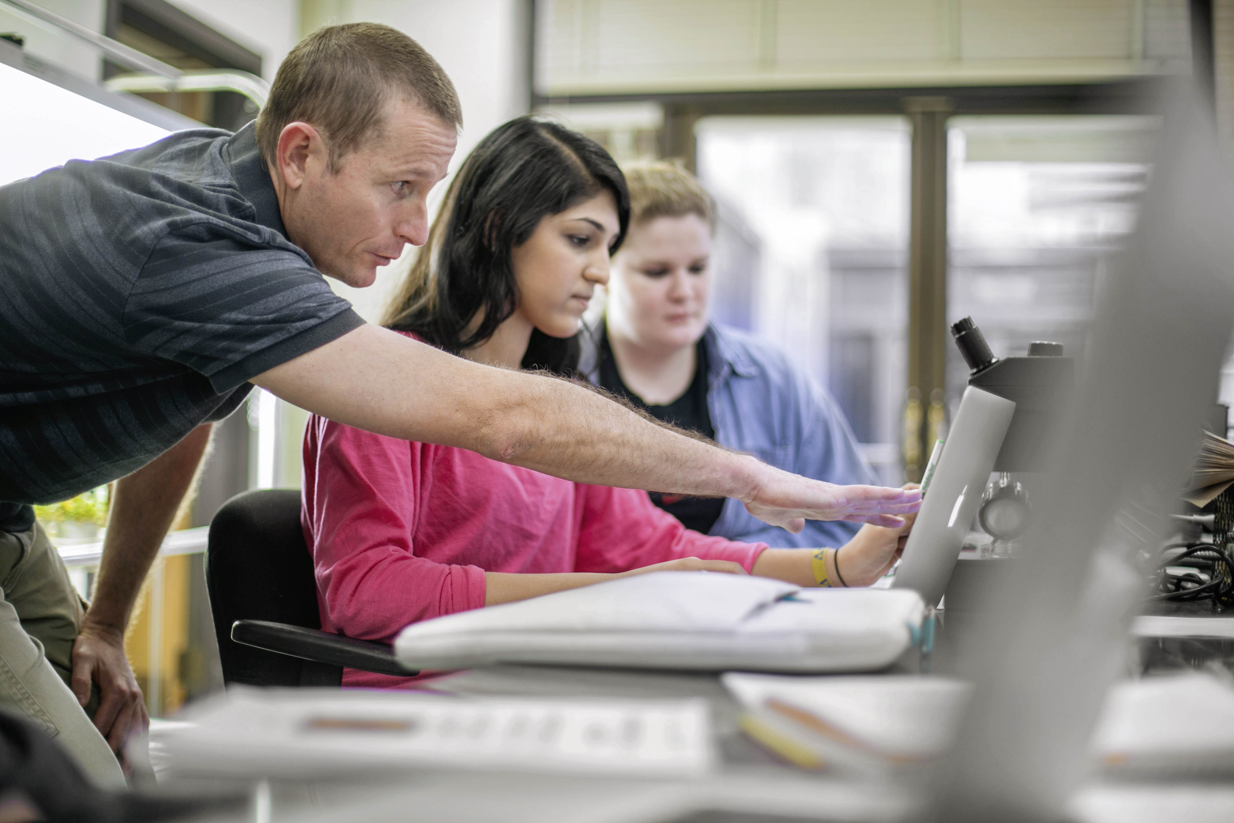 a professor working with a student points to a computer screen