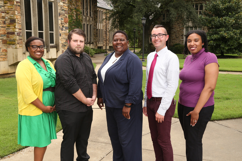 two men and three women pose outside