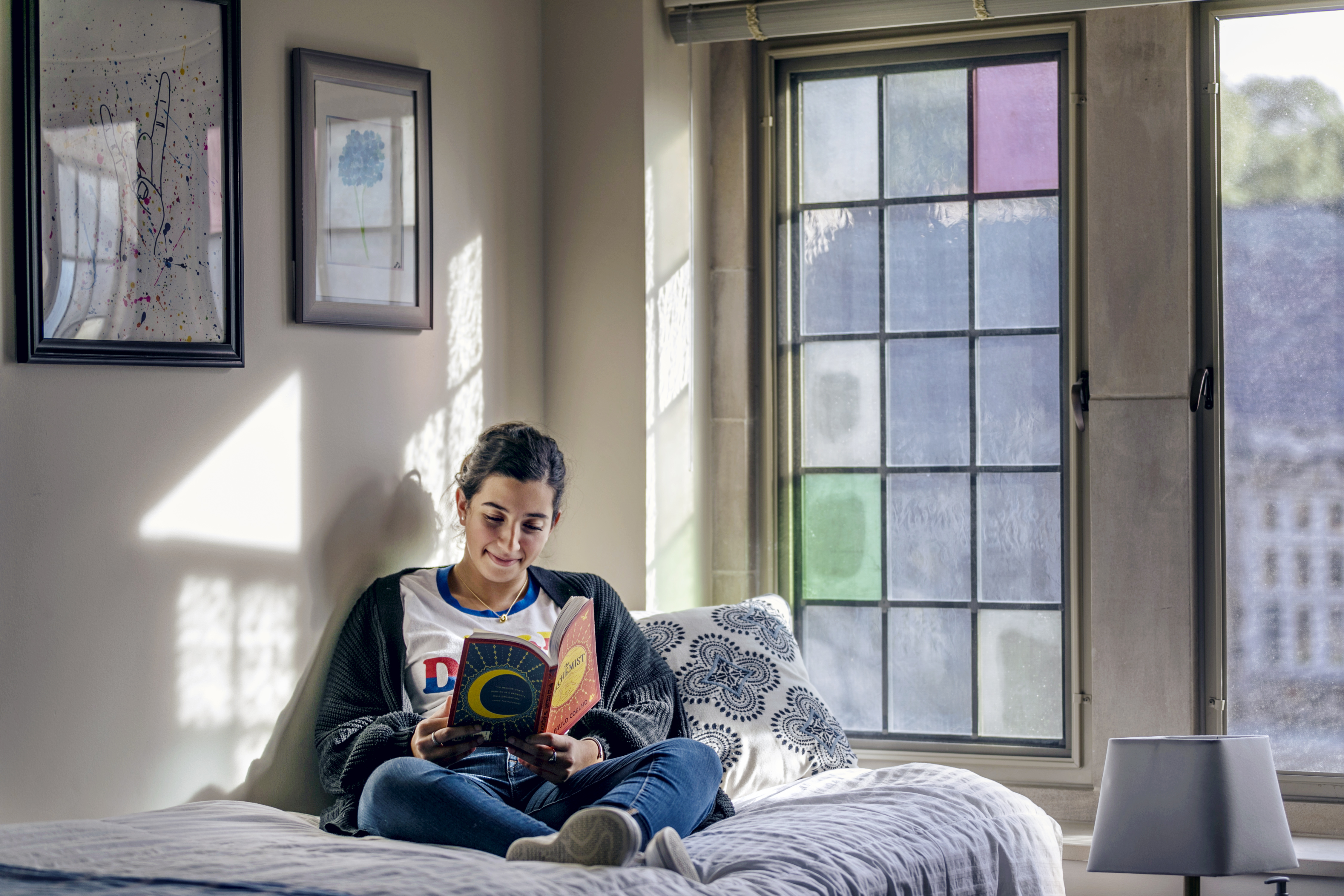 a female reading a book in her dorm room