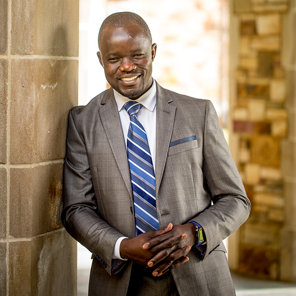 A well dressed professor stands in front of a window