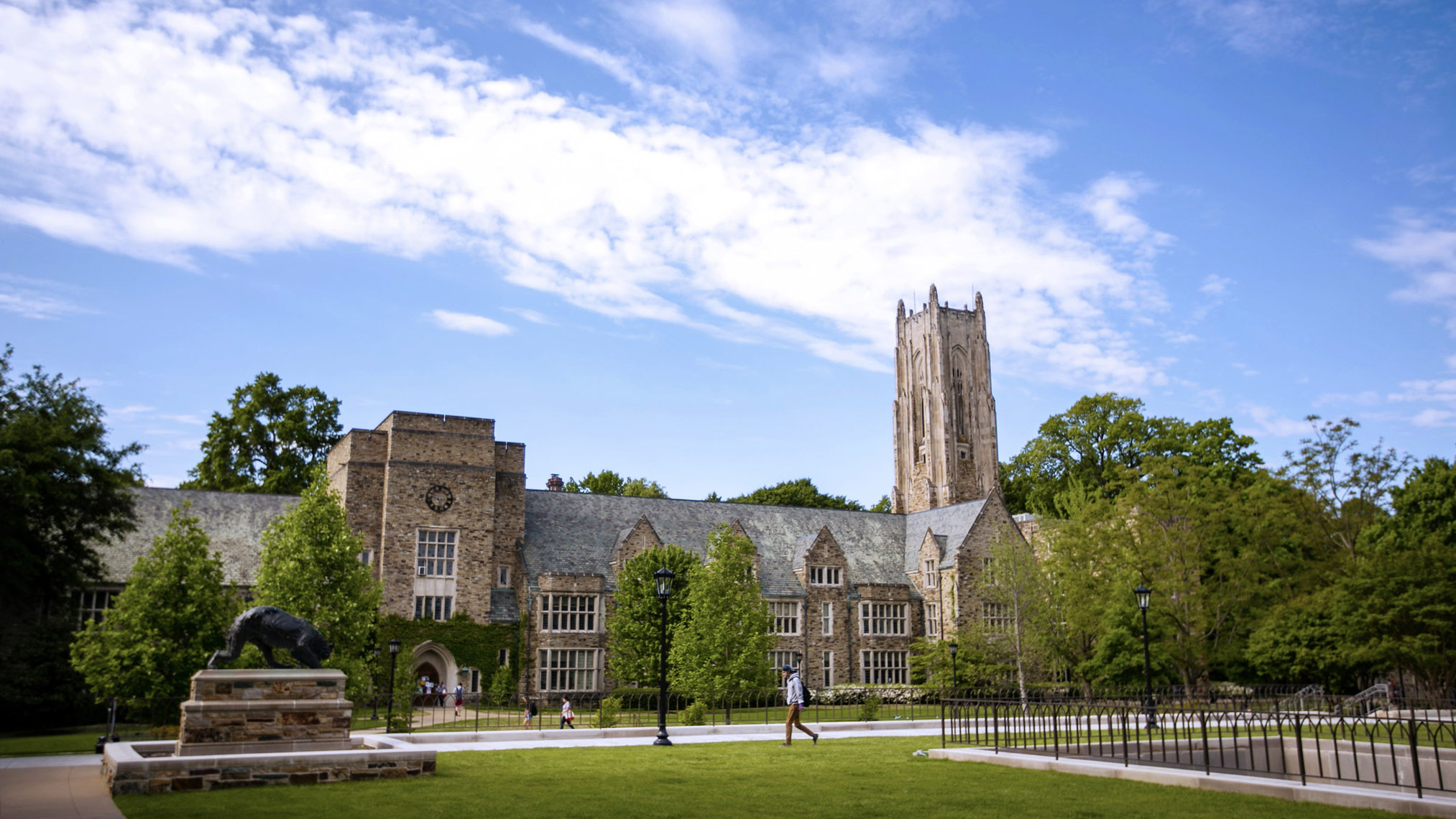 a wide shot of a Gothic stone building and a student walking 