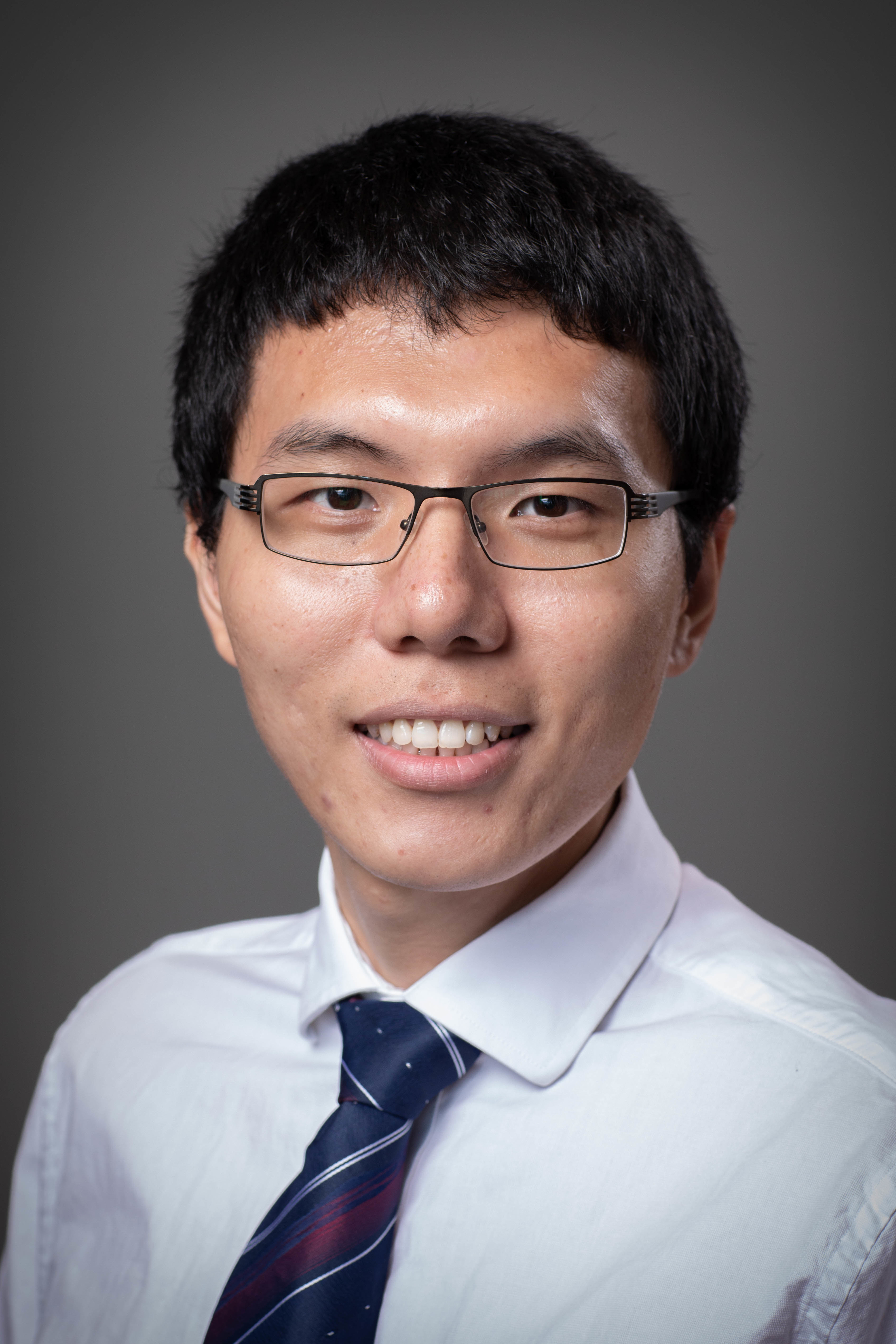 head shot of a young Asian man wearing glasses