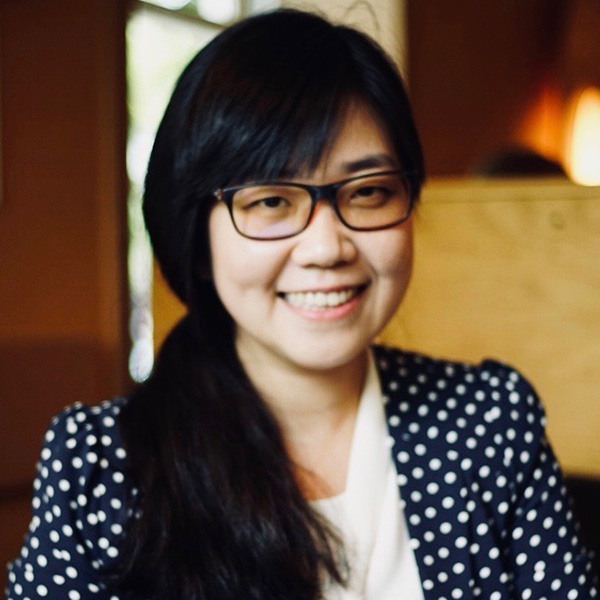 an Asian woman with long hair and glasses smiles at the camera