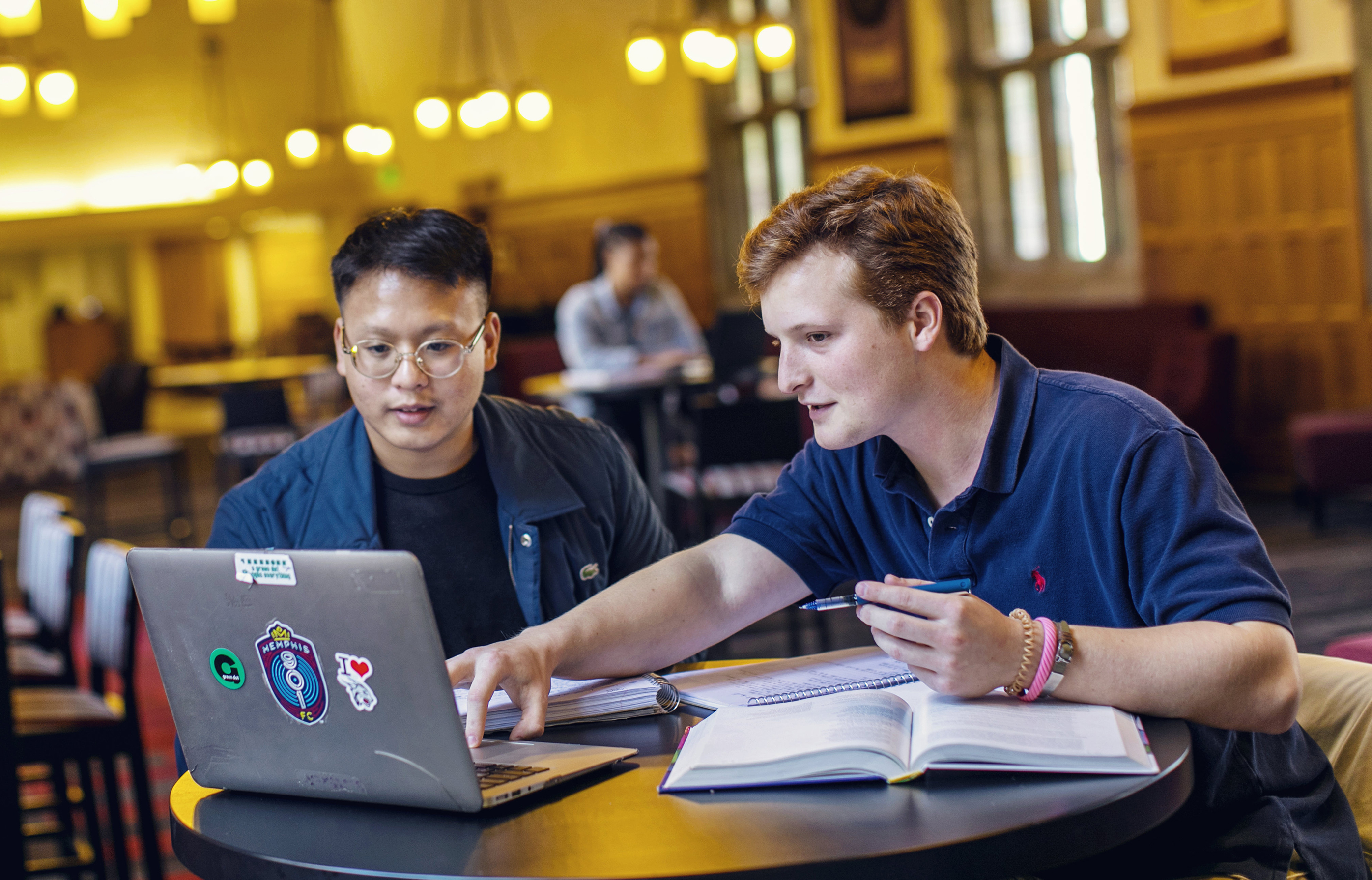 two male students look at a laptop