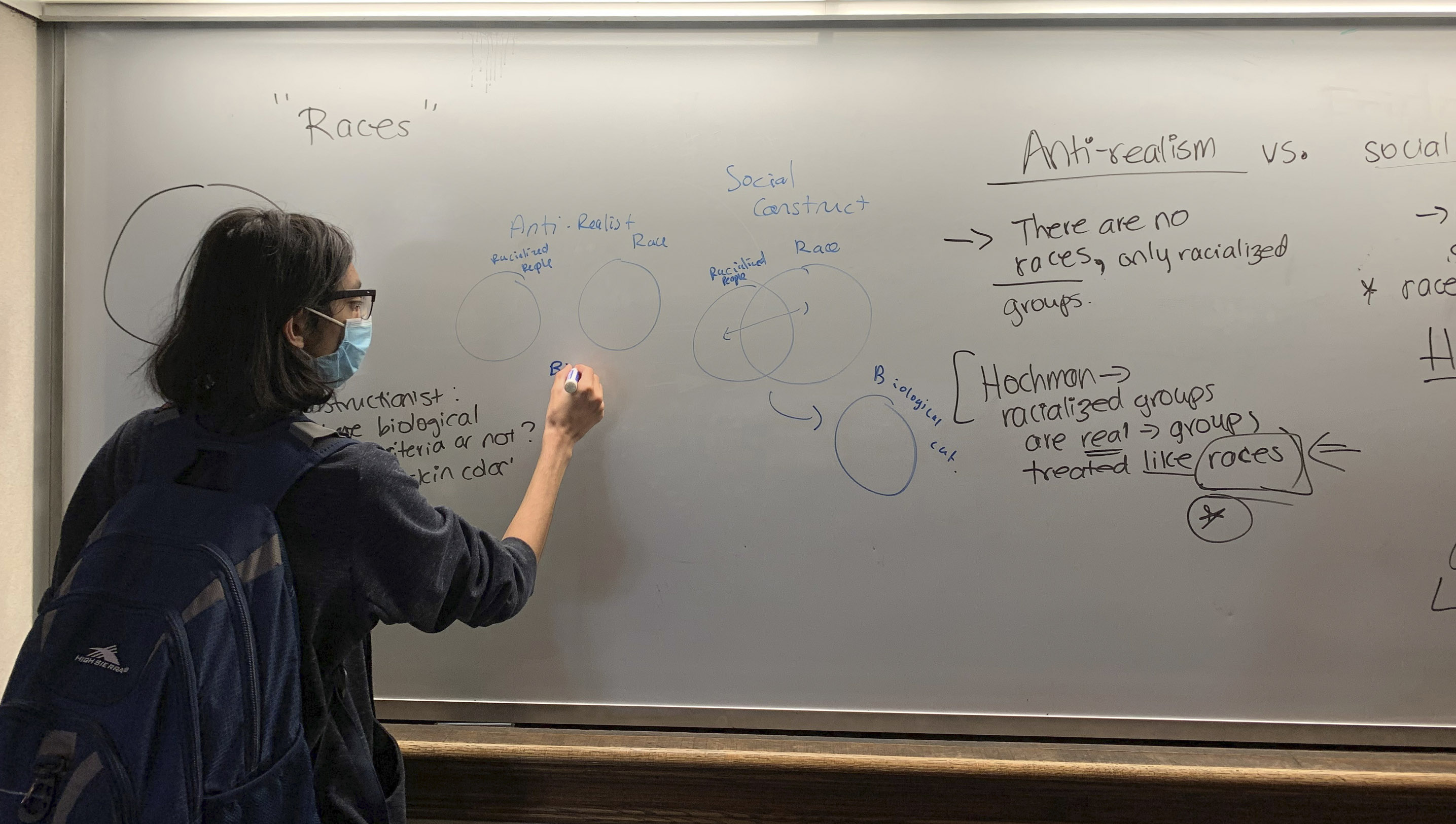a student writes at a whiteboard