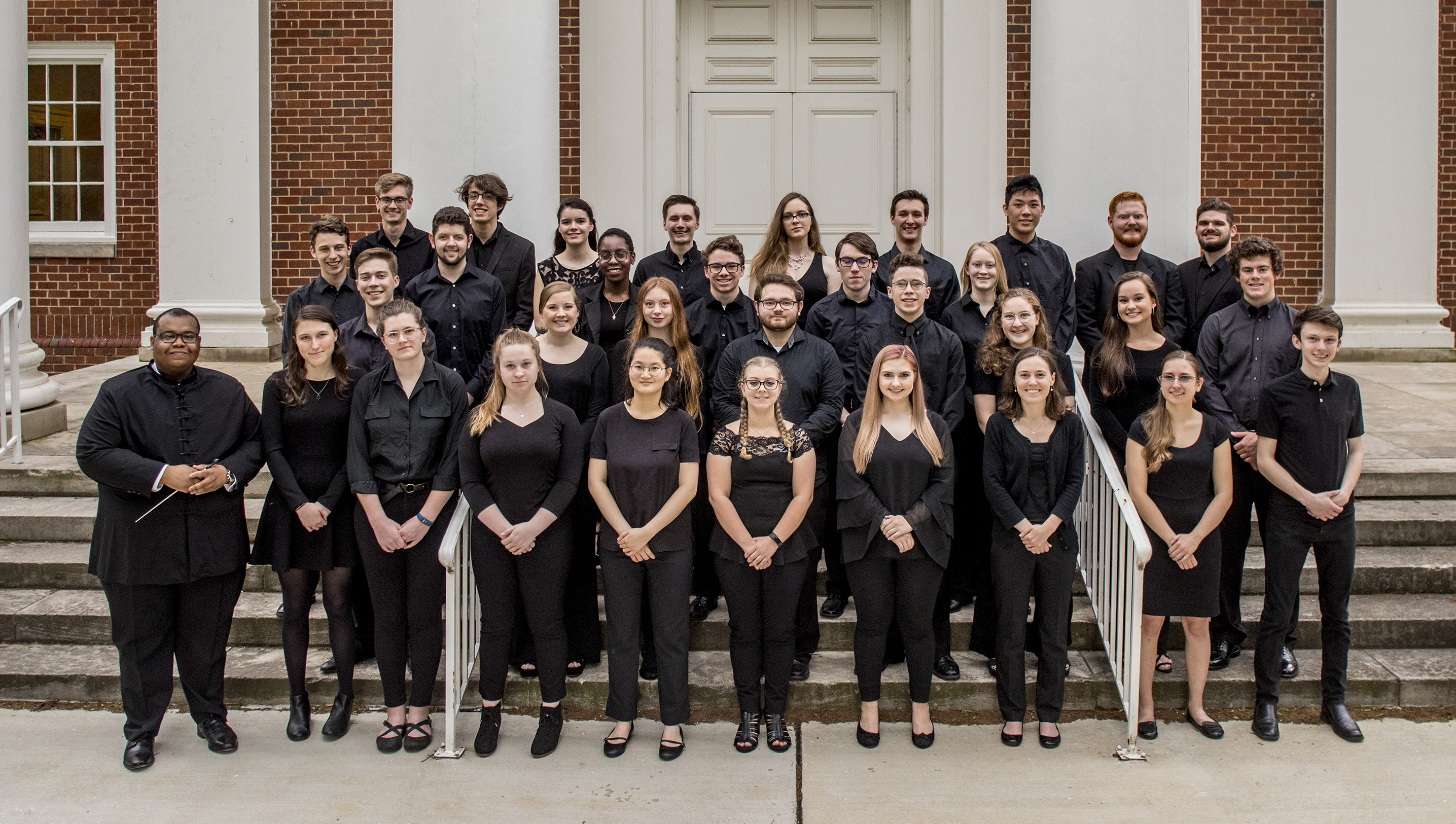 an orchestra poses on the steps of a concert hall