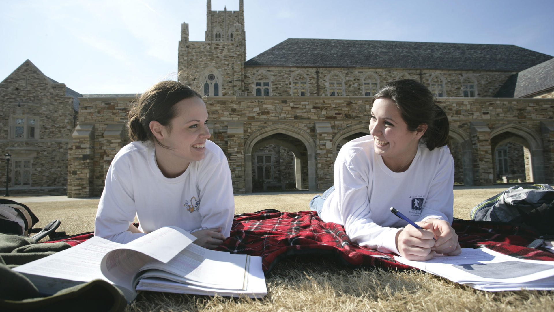 two female students study on the lawn of the library