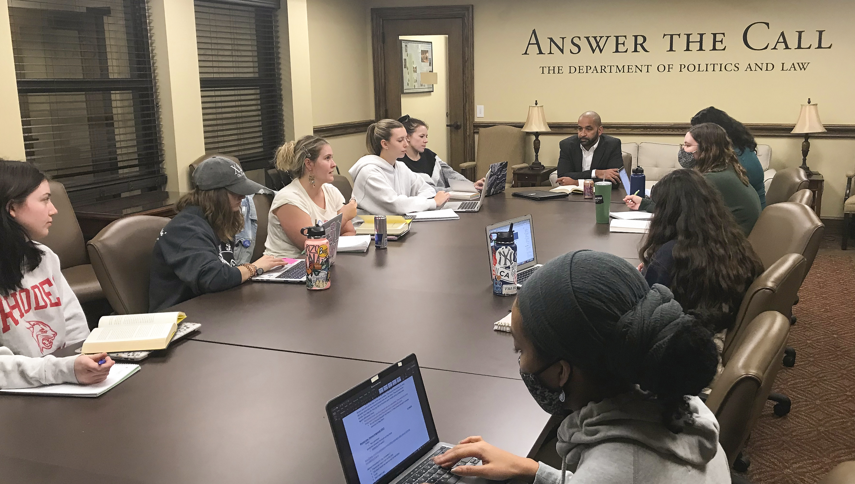 a professor meets with a class around a conference table