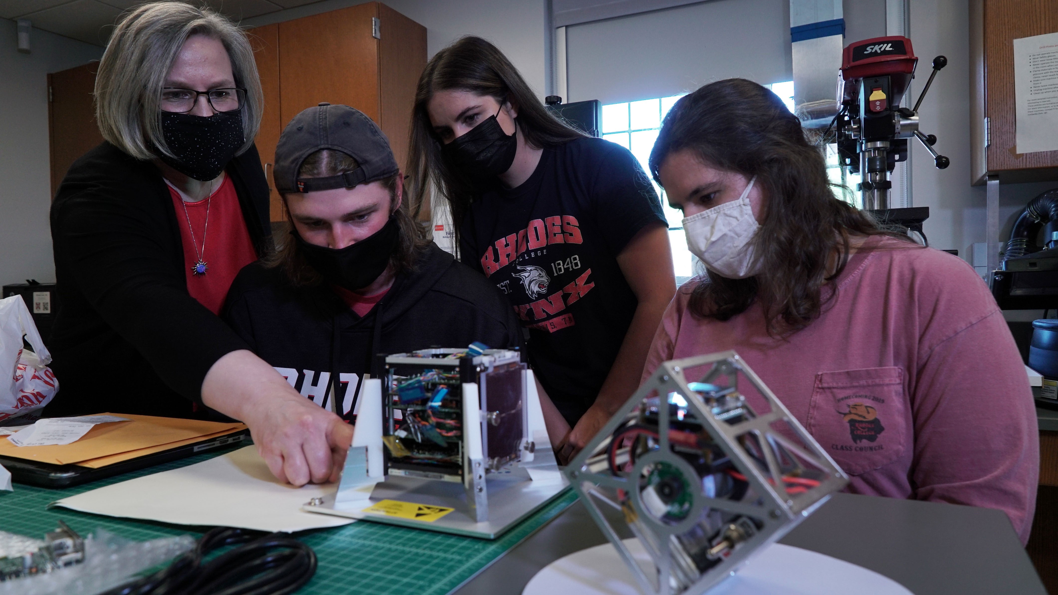 a professor and students work on a satellite research project