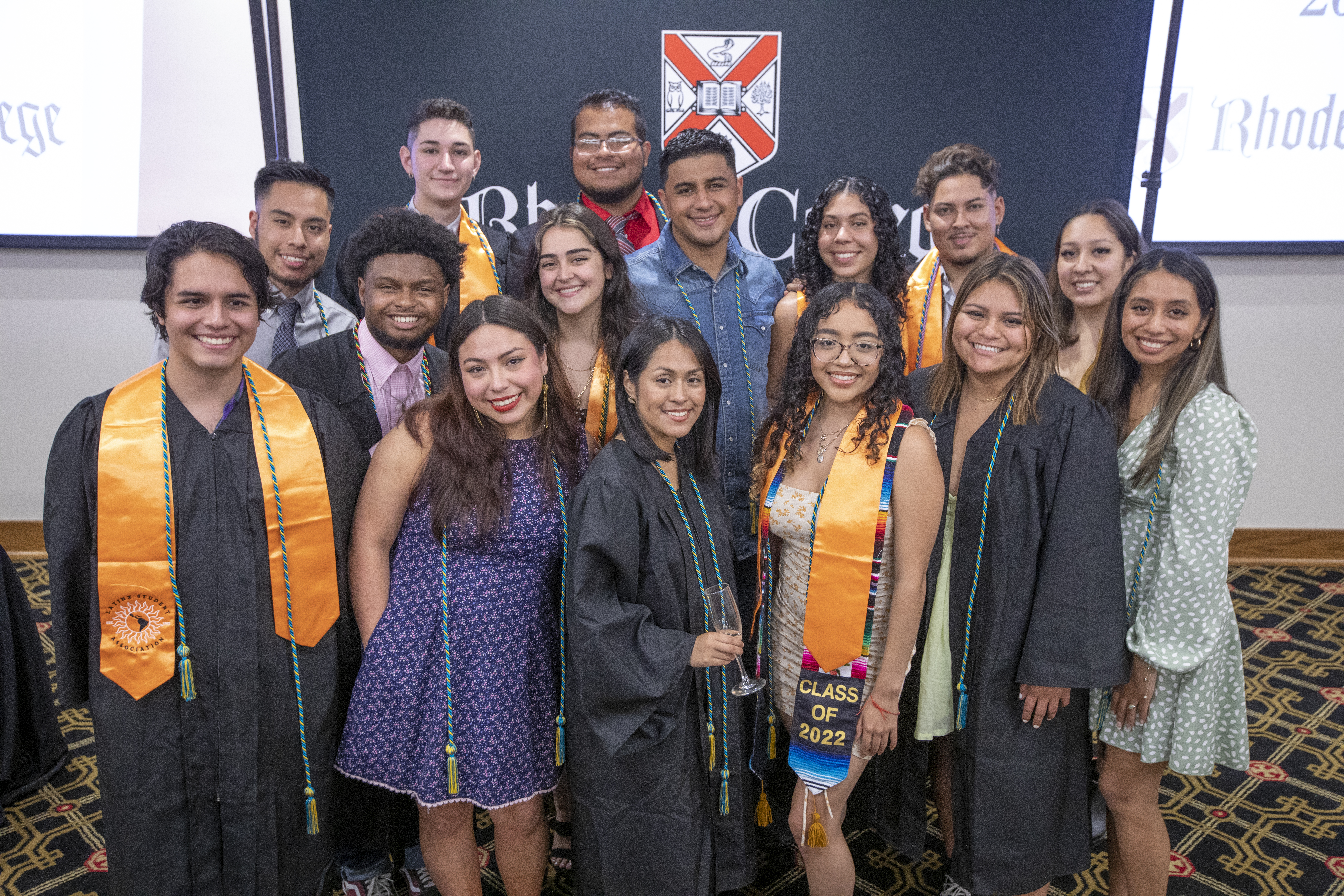 Group of Latinx students at Rhodes College wearing graduation regalia, cords, and stoles.