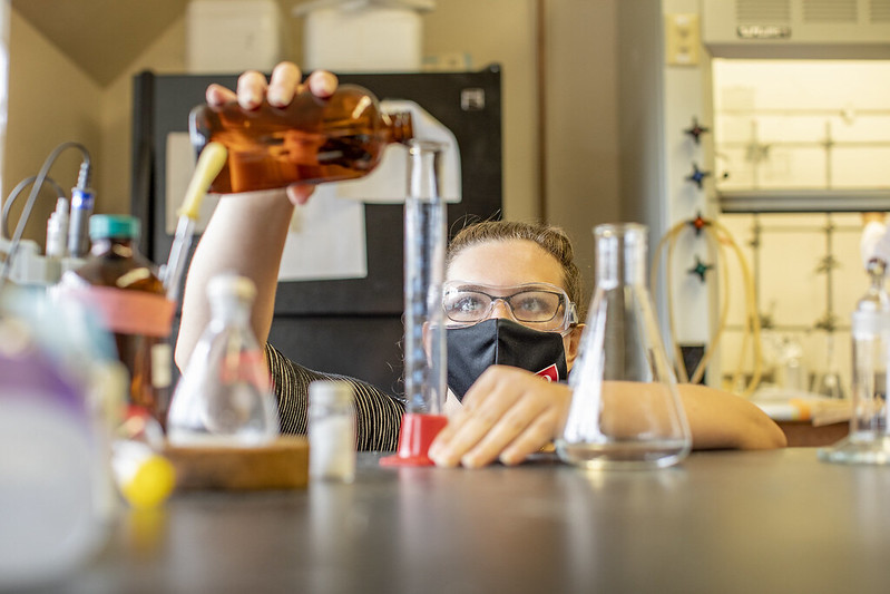 A student carefully measures a red liquid.