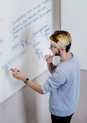 a student works an equation on a whiteboard