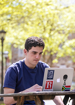 a young man studies a computer outside
