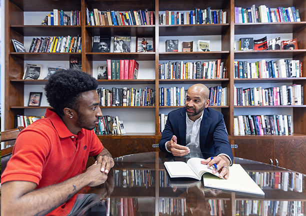 a professor and student talk at a table