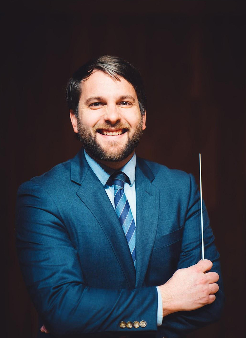 a man in a blue suit holding a conductor's baton