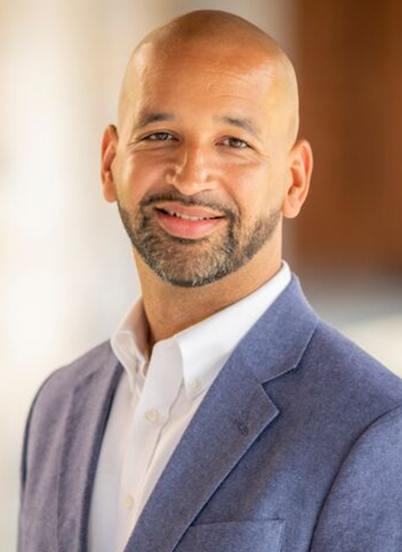 an African American man in a light blue jacket smiles at the camera