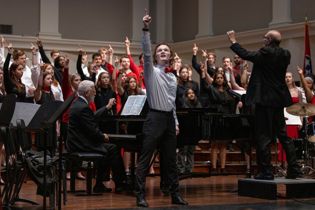 A choir sings with hands raised