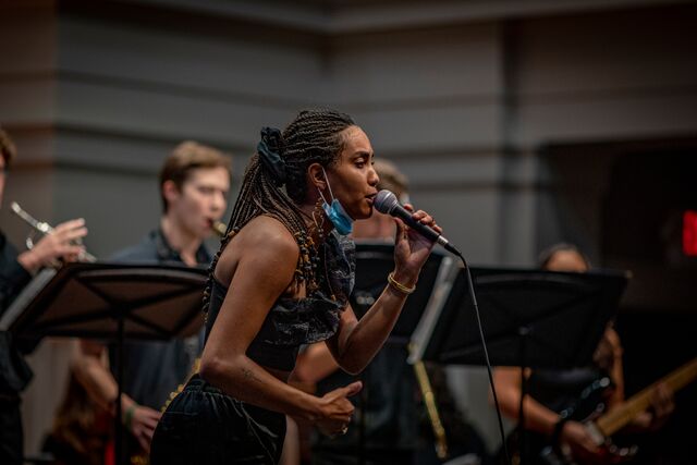 A woman singing in front of a band.