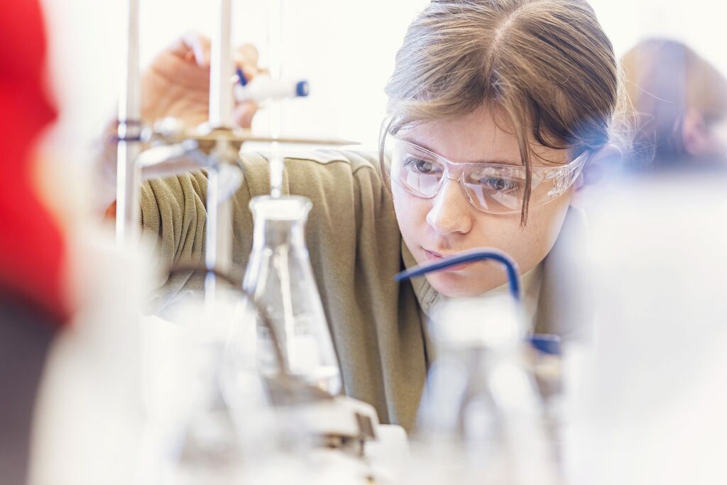 A young woman precisely measures liquid in a test tube.